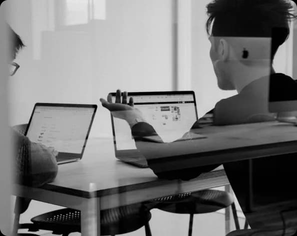 Person working across two laptops in a meeting room